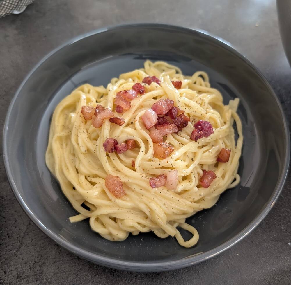 A grey bowl of carbonara: linguine with crisped guanciale and black pepper