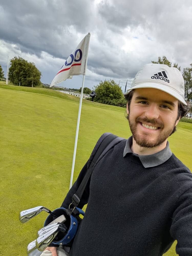 A selfie on the green beside the pin, golf bag over the shoulder
