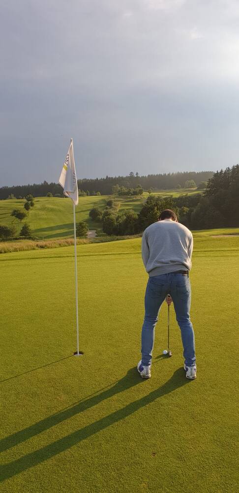Lining up a putt beside the flag in low evening light