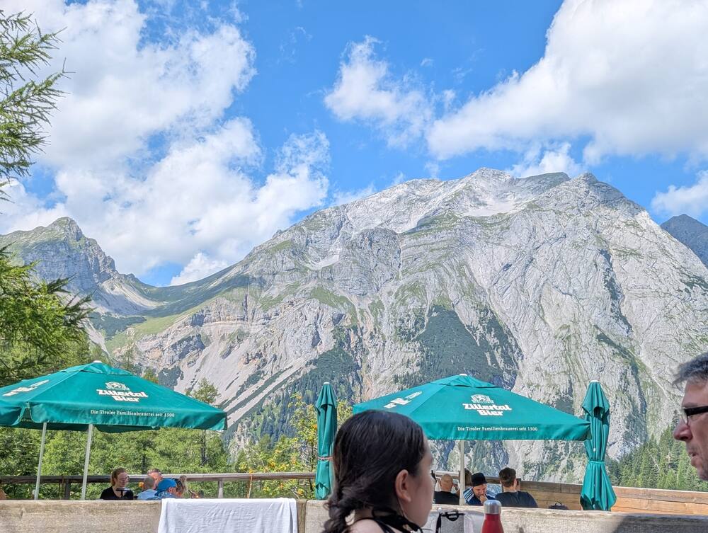 A limestone face rising behind the parasols of a mountain hut terrace