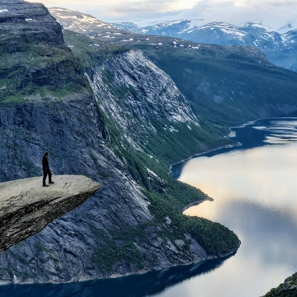 A lone figure at the end of the Trolltunga rock ledge, high above a Norwegian fjord