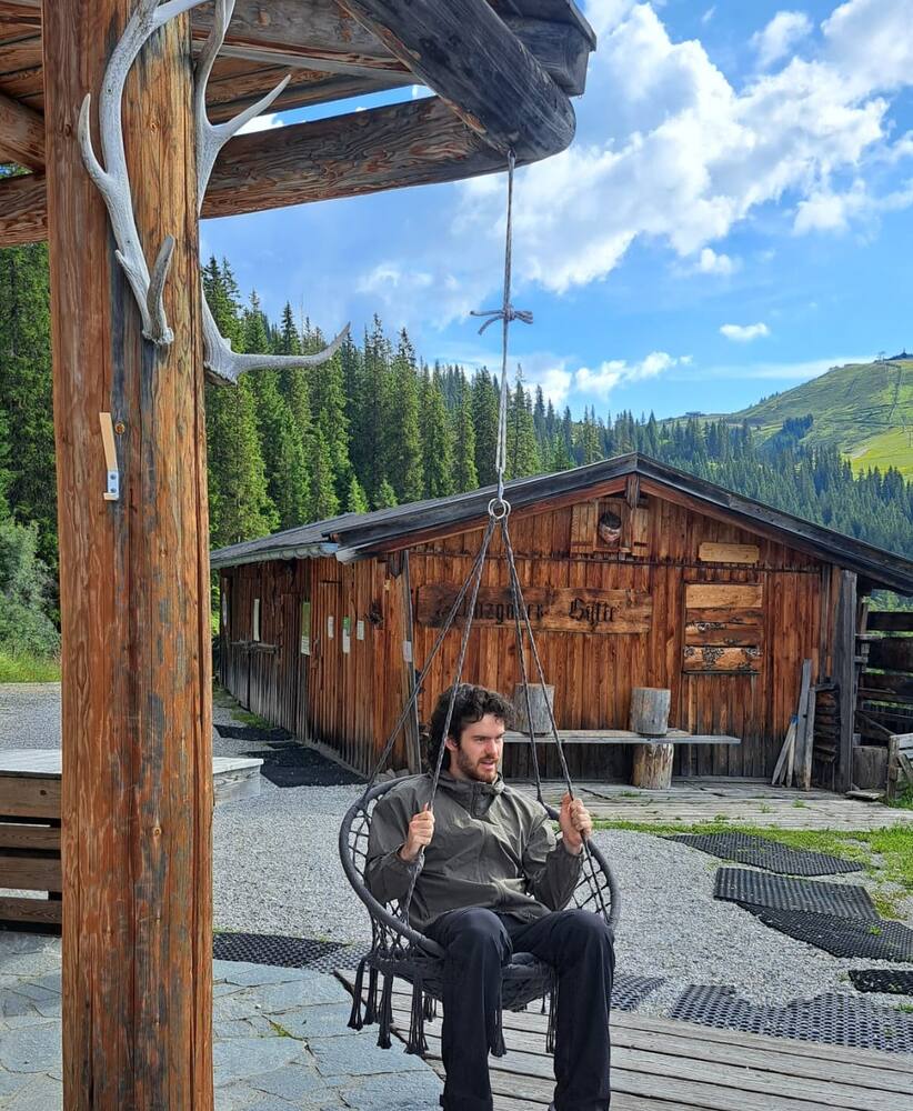Sitting in a hanging chair on the deck of a timber alpine hut