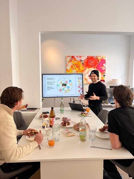Autegro &middot; the brand strategy workshop, three people around a table with the brand sprint questions up on the screen